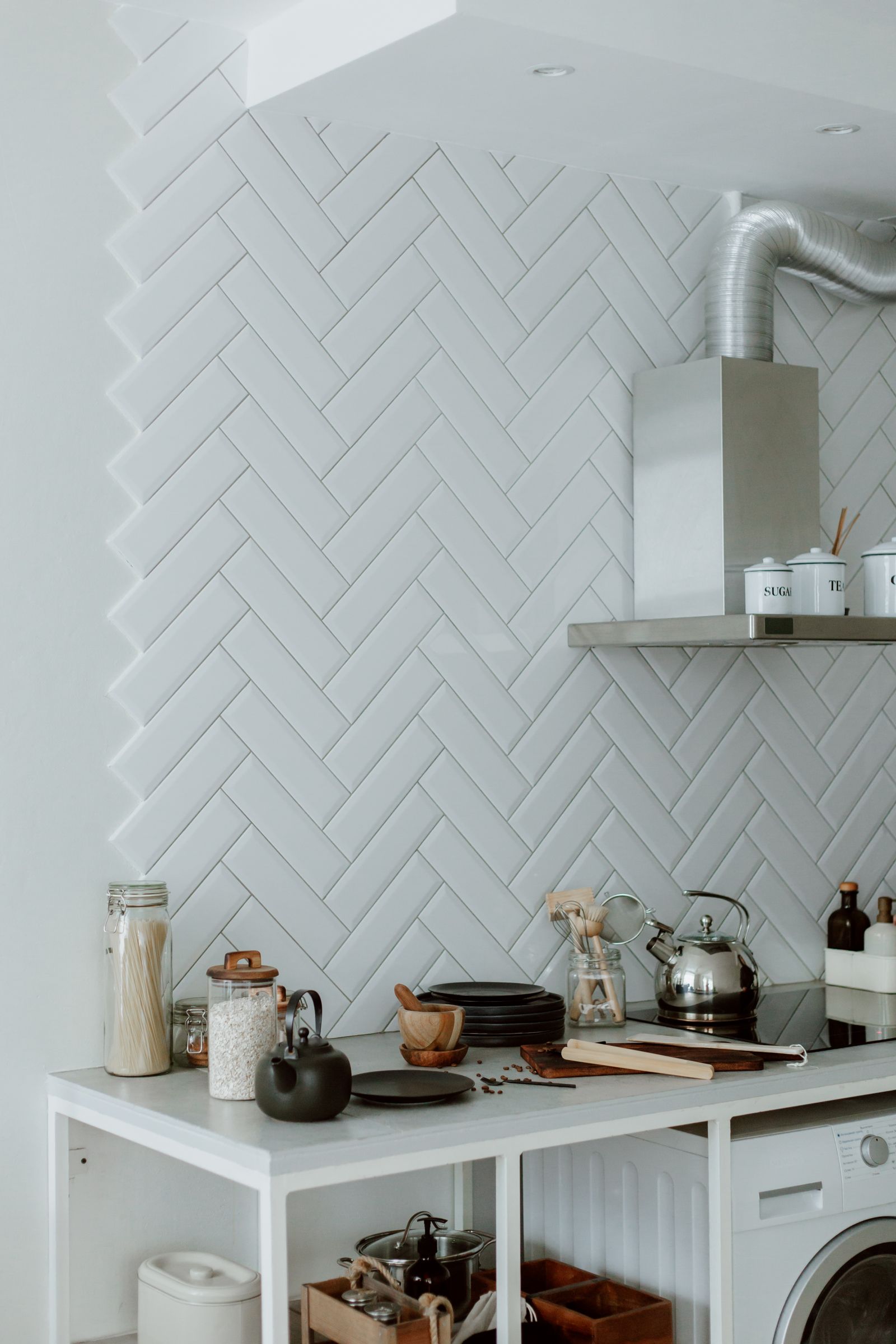 A white herringbone tile backsplash running behind a kitchen counter