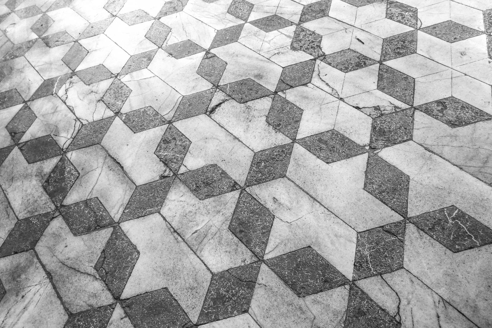 A floor of grey and white marble tiles cut into a three-dimensional cube pattern