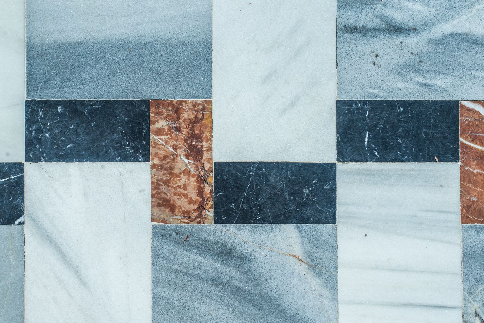 Polished marble tiles in blue, white and rust laid up in a checkerboard pattern